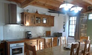 A kitchen with wooden cabinets, a tiled backsplash, a coffee maker, and a dining table with chairs. - Charming furnished holiday home in the heart of the medieval quarter...  (Murat)