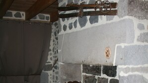Una habitación rústica con chimenea de piedra, vigas de madera, una mesa de madera y un sofá estampado.