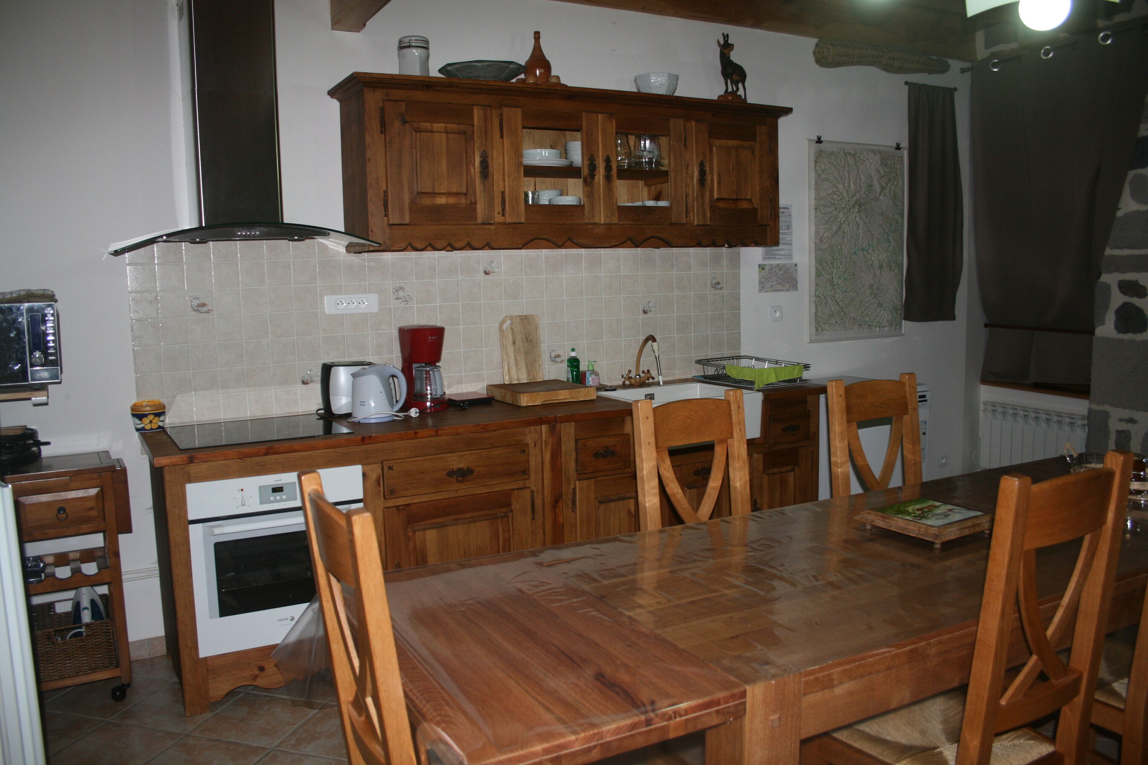 A kitchen with wooden cabinets, a tiled backsplash, a wooden dining table, and chairs.