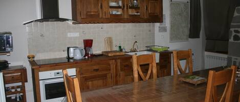 A kitchen with wooden cabinets, a tiled backsplash, a wooden dining table, and chairs.