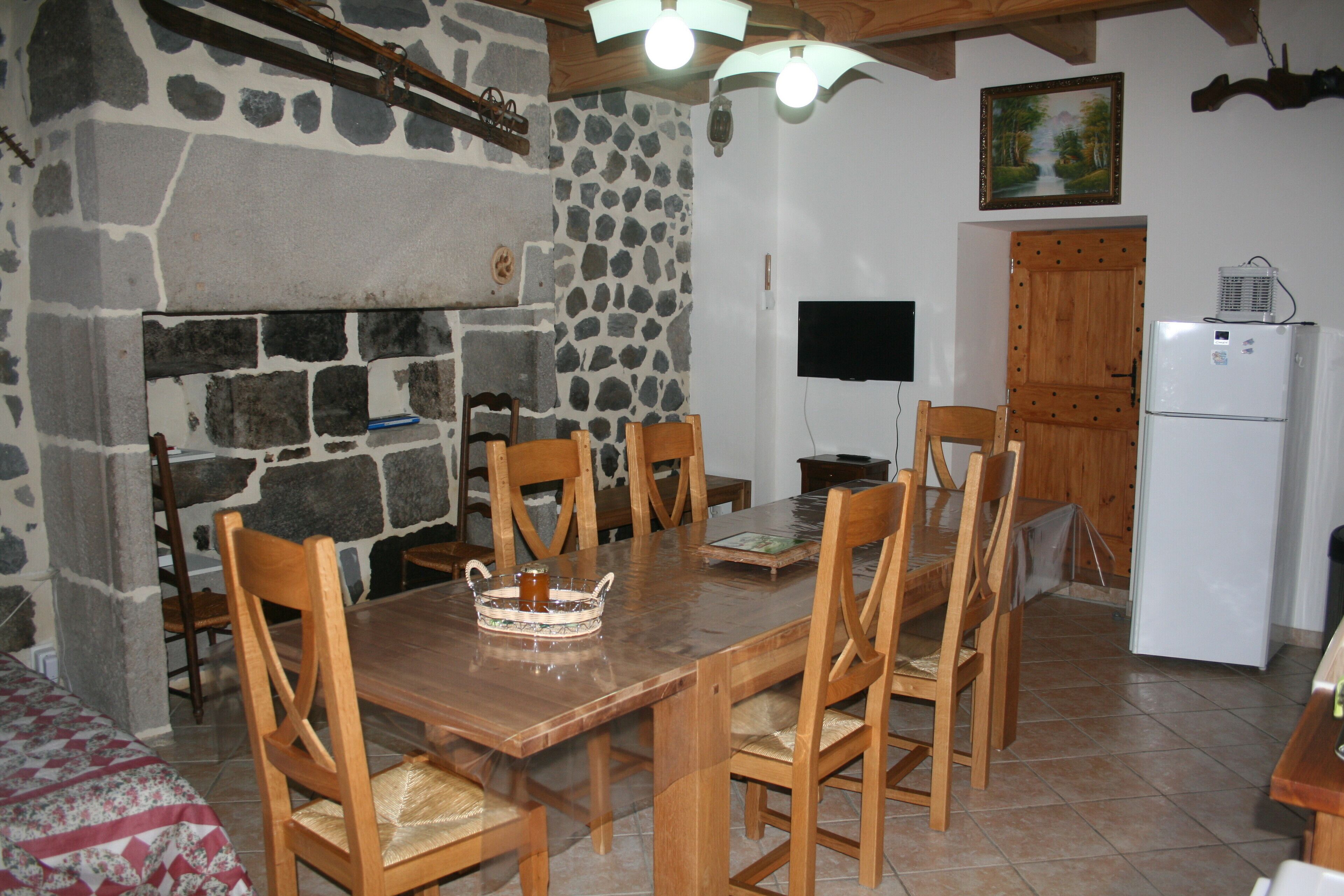 Un coin repas agrémenté d’une cheminée en pierre, de chaises en bois et d’une table en bois.