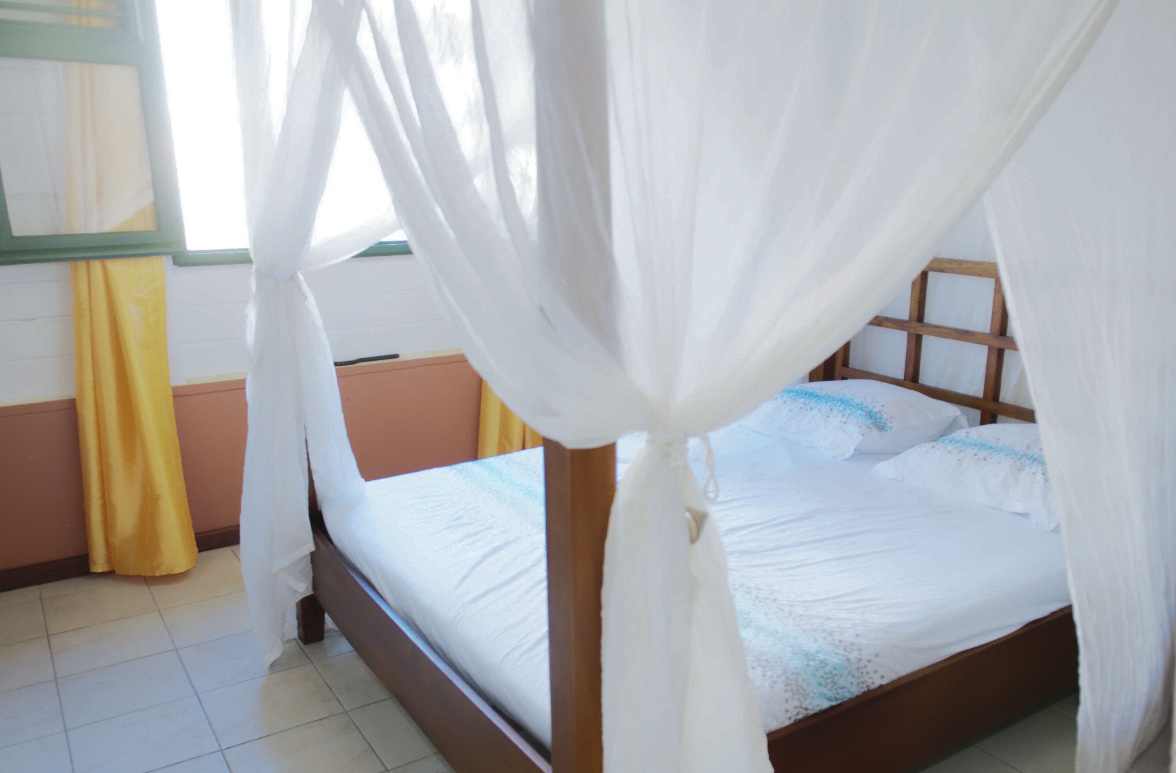 A bed with a wooden frame, white bedding, and a canopy.