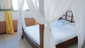 Una cama con estructura de madera, ropa de cama blanca y dosel.