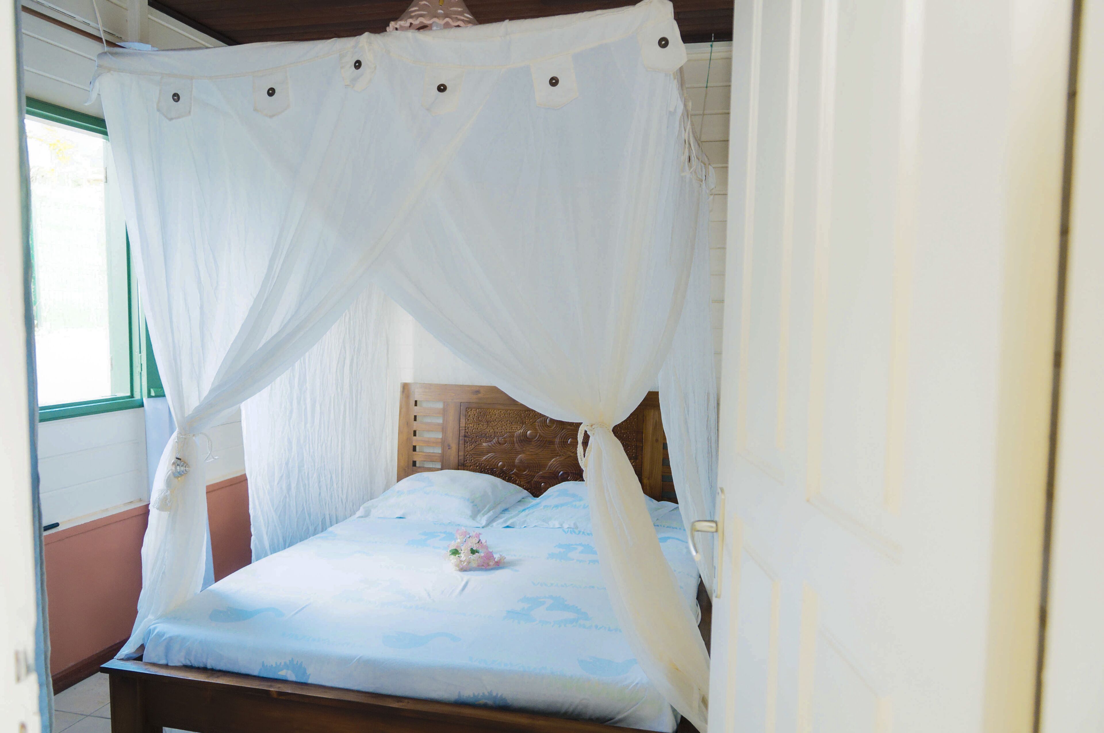 A bed with a canopy, wooden headboard, and a floral pillow.