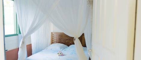 A bed with a canopy, wooden headboard, and a floral pillow.
