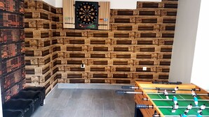 A room with a dartboard, a foosball table, and a wall of stacked wooden crates. - A trip into nature (Bollendorf)