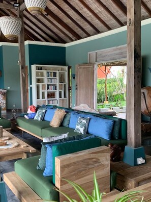 A cozy living area with a green sofa, wooden coffee table, and a bookshelf.