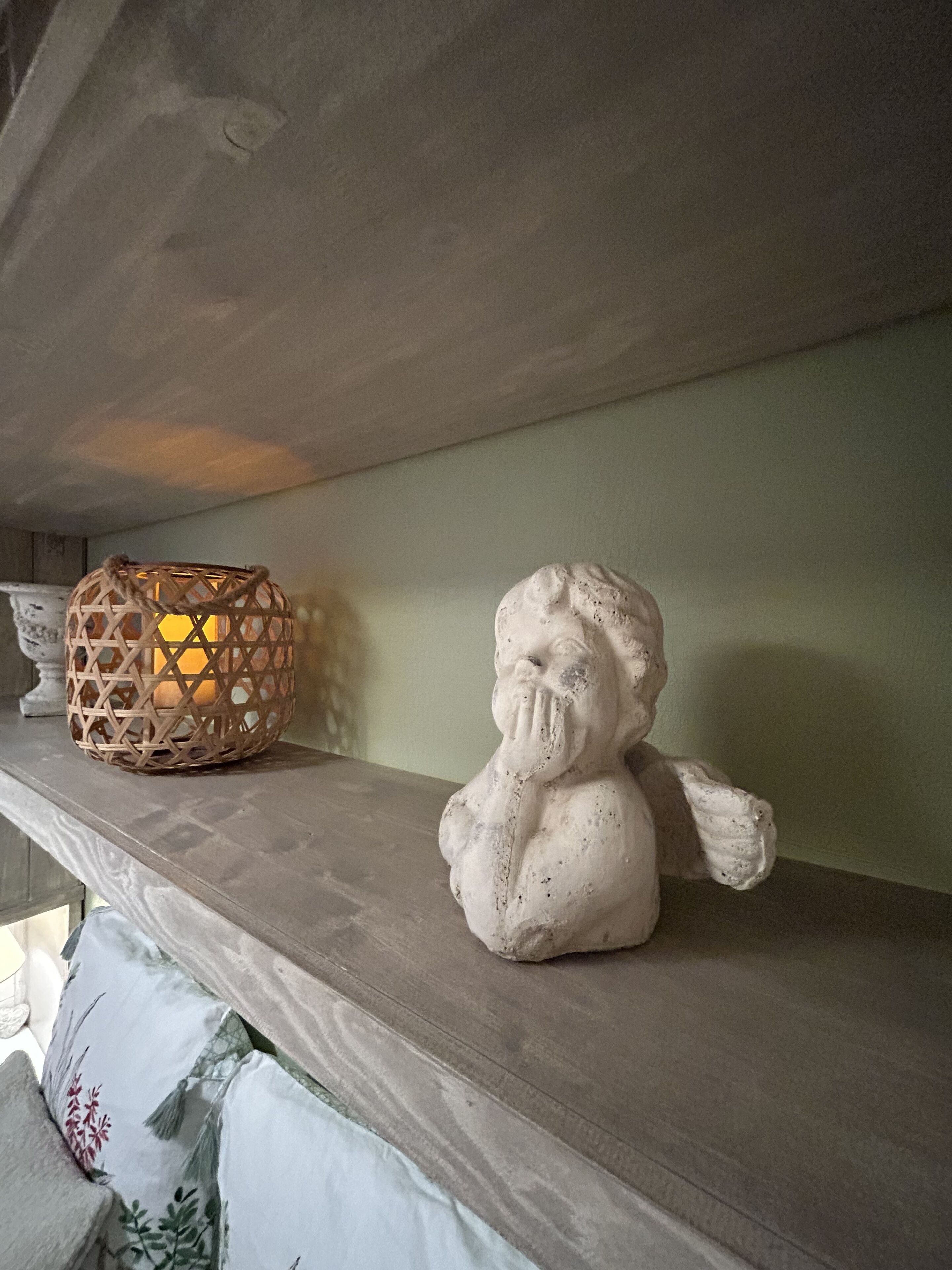 A shelf with a textured wall, a woven basket, and a white statue.