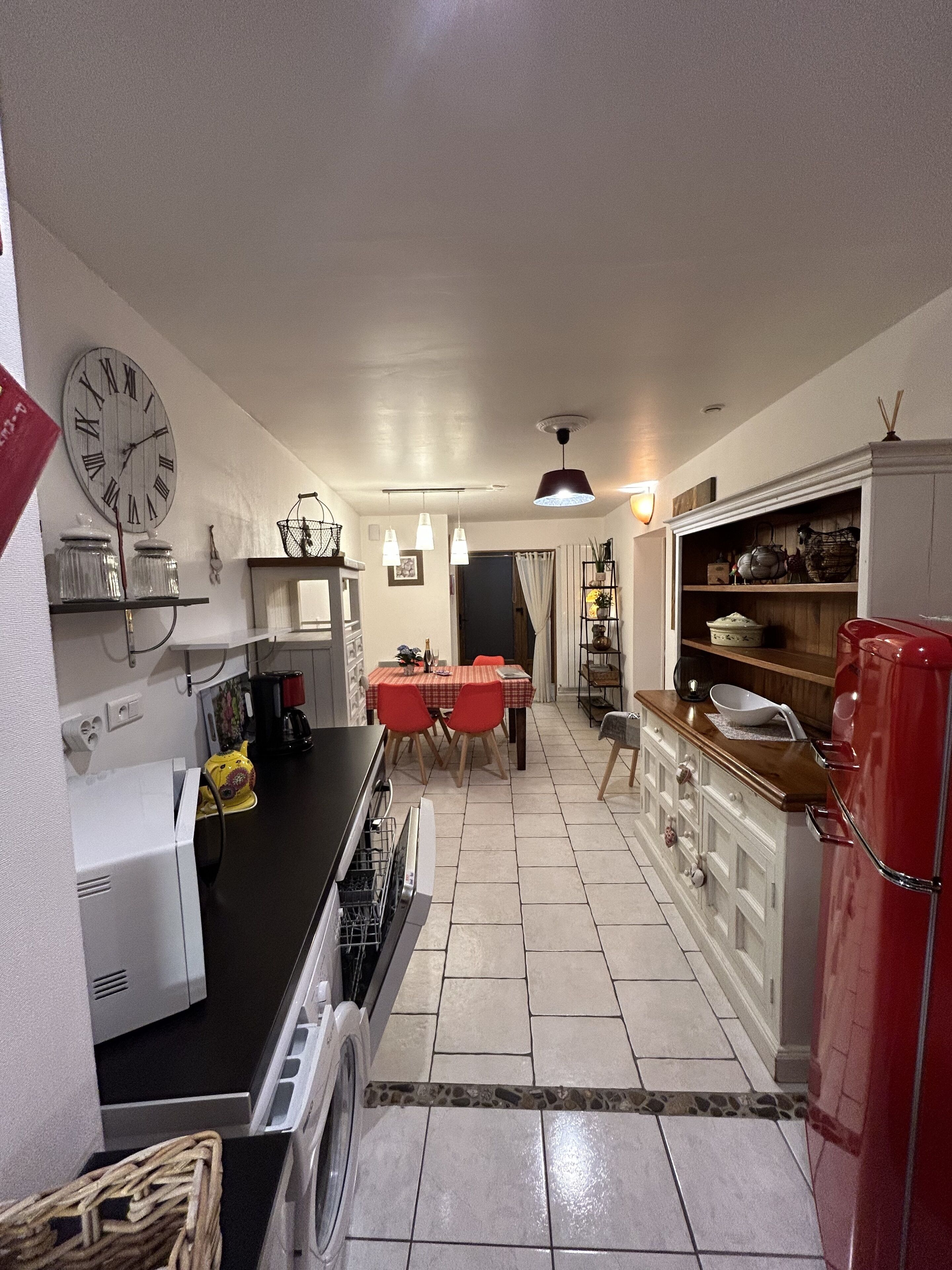 Una cocina compacta con lavadora, comedor con mesa y sillas, y un refrigerador rojo.