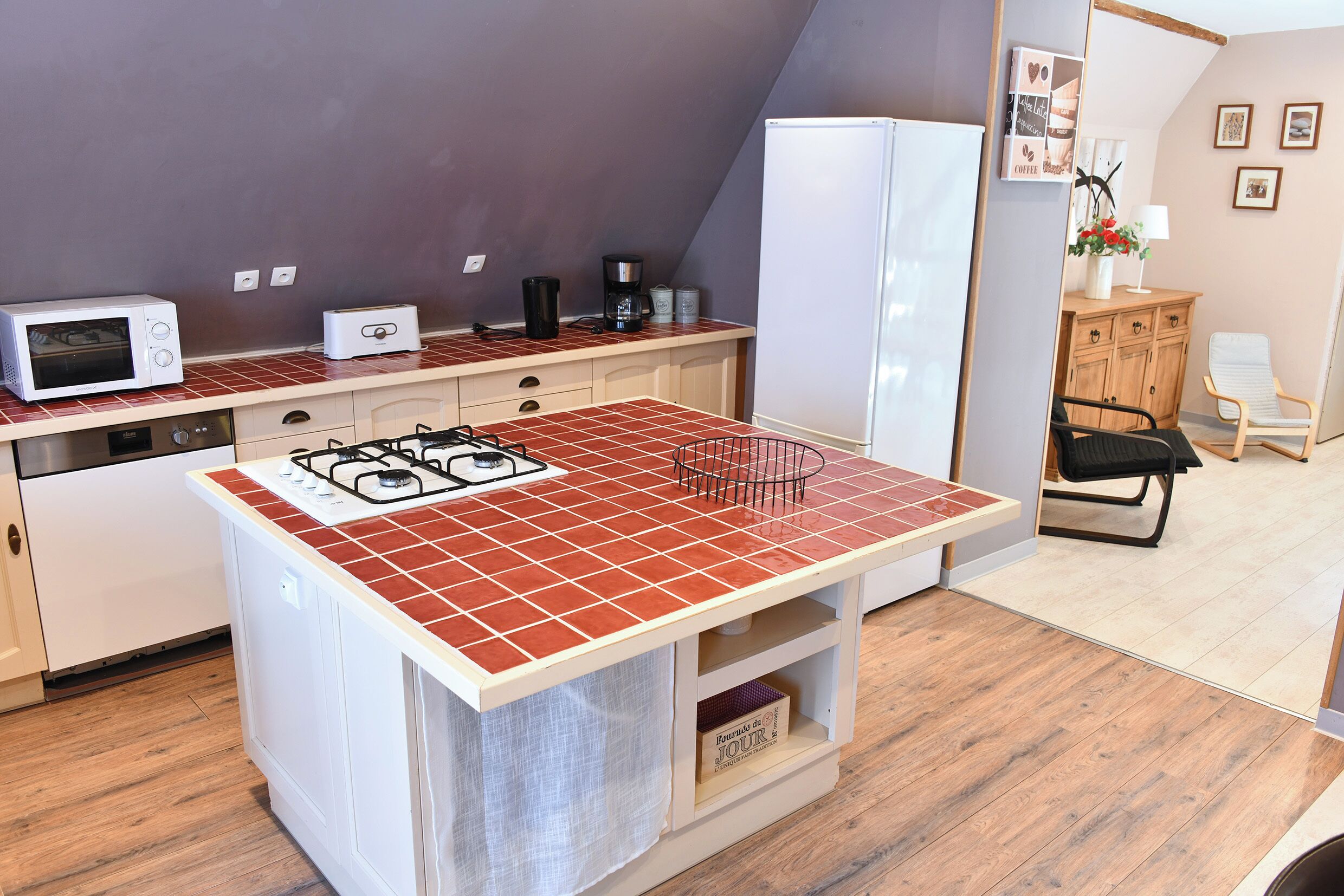 A compact kitchen with a gas stove, microwave, toaster, and coffee maker.