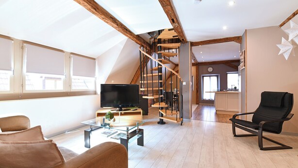 A spacious living room with a modern design, featuring a large TV, comfortable seating, and a wooden staircase. - Villa Joseph **, Apartment 4 people in Kaysersberg - 2 bedrooms (Kaysersberg-Vignoble)