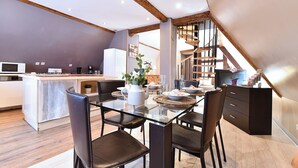 A modern kitchen with a glass dining table, dark chairs, and wooden beams. - Villa Joseph **, Apartment 4 people in Kaysersberg - 2 bedrooms (Kaysersberg-Vignoble)