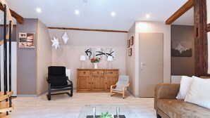 A living room with a sofa, a coffee table with a plant, a wooden cabinet, and a chair. - Villa Joseph **, Apartment 4 people in Kaysersberg - 2 bedrooms (Kaysersberg-Vignoble)
