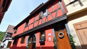A traditional half-timbered building with a red facade, wooden door, and a visible mailbox. - Villa Joseph **, Apartment 4 people in Kaysersberg - 2 bedrooms (Kaysersberg-Vignoble)