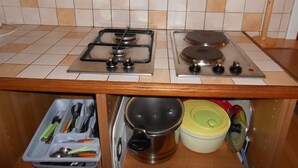 A kitchen with a gas stove, two burners, and a range hood. There are two electrical outlets on the wall and a wooden spoon rack. - 4-seater apartment 50 m2 (Laruns)