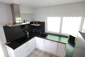 A modern kitchen with white cabinets, black countertops, and a window providing natural light.