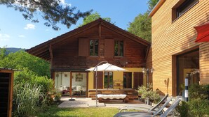 Una casa de madera con un patio, mobiliario exterior y un jardín.