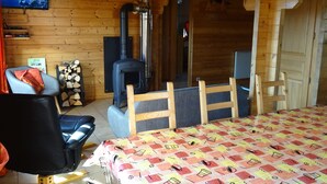 A cozy cabin room with a wooden interior, a fireplace, a television, and a bed with a patterned bedspread.