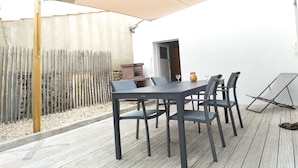 Un patio con mesa y sillas, un paraguas grande y una valla de madera.