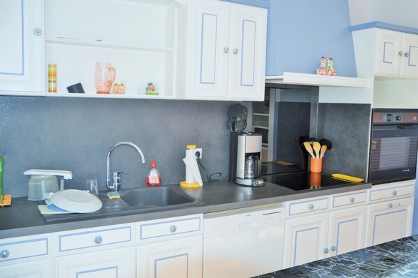 A kitchen with white cabinets, a black countertop, and a stainless steel sink.