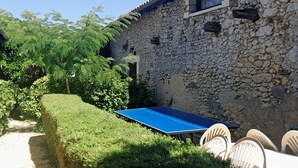 A stone building with a blue ping pong table and outdoor seating.