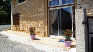 A stone building with a large sliding glass door, two potted plants, and a small window.