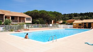 Una piscina con bordo piastrellato, circondata da edifici e alberi.