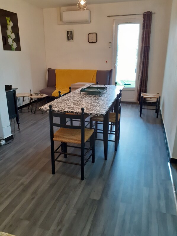 A dining area with a table and chairs, a sofa, a small table with a bowl, and a picture on the wall.