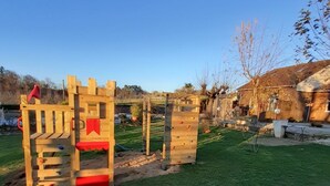 Une structure de jeu en bois, installée dans un espace herbeux, sous un ciel dégagé.