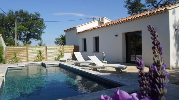 A pool area with lounge chairs and a small building with a tiled roof. - VILLA LES GRANGES- SWIMMING POOL surrounded by a green park overlooking the mountains  (Saint-Marcellin-Lès-Vaison)