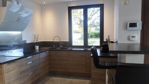 A modern kitchen with wooden cabinets, a stainless steel sink, and a large window. - VILLA LES GRANGES- SWIMMING POOL surrounded by a green park overlooking the mountains  (Saint-Marcellin-Lès-Vaison)