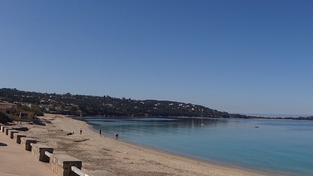 A beach with a clear sky, calm water, and a stone barrier. - Rental Porticcio Agosta Air conditioning 200 m from the sea, garden and barbecue (Albitreccia)