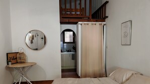 A bedroom with a bed, a small table with a mirror, and a view into the kitchen. - Rental Porticcio Agosta Air conditioning 200 m from the sea, garden and barbecue (Albitreccia)