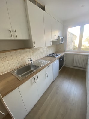 A modern kitchen with white cabinets, a stainless steel sink, and a microwave. - Facing the sea Bright, spacious T3 apartment near Thalasso and Casino (Pornichet)