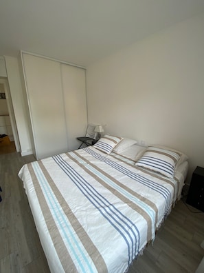 A bedroom with a large bed, a nightstand, a lamp, and a wardrobe. - Facing the sea Bright, spacious T3 apartment near Thalasso and Casino (Pornichet)