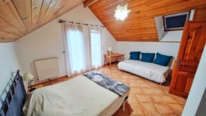 Une chambre confortable avec un plafond en pente, un lit, un canapé, une petite table et un radiateur.