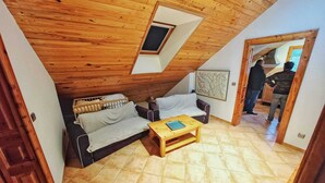 Une chambre mansardée chaleureuse avec un plafond en pente, un plancher en bois, un canapé, une petite table et une fenêtre.