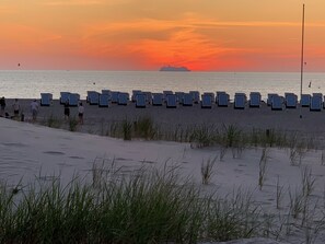 A beach with rows of blue and white striped beach chairs and a ship in the distance.