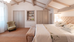 Une chambre à coucher comprenant un lit, un banc, une chaise et des placards intégrés.