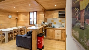 L’intérieur d’un chalet en bois comprend un coin repas, une cuisine et un canapé.