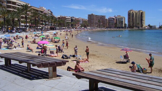 A beach with palm trees, beachgoers, and a clear sky. - 2-bedroom apartment community pool WIFI close to beaches (TORREVIEJA)