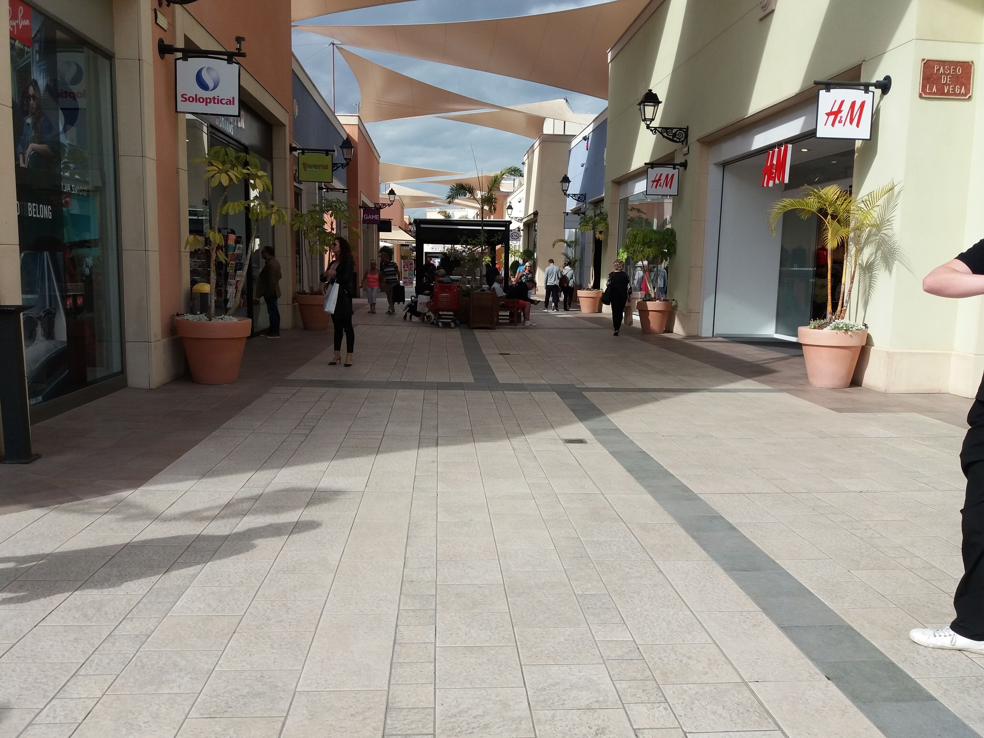 A shopping mall corridor with stores like Solopical, Game, and H&M.