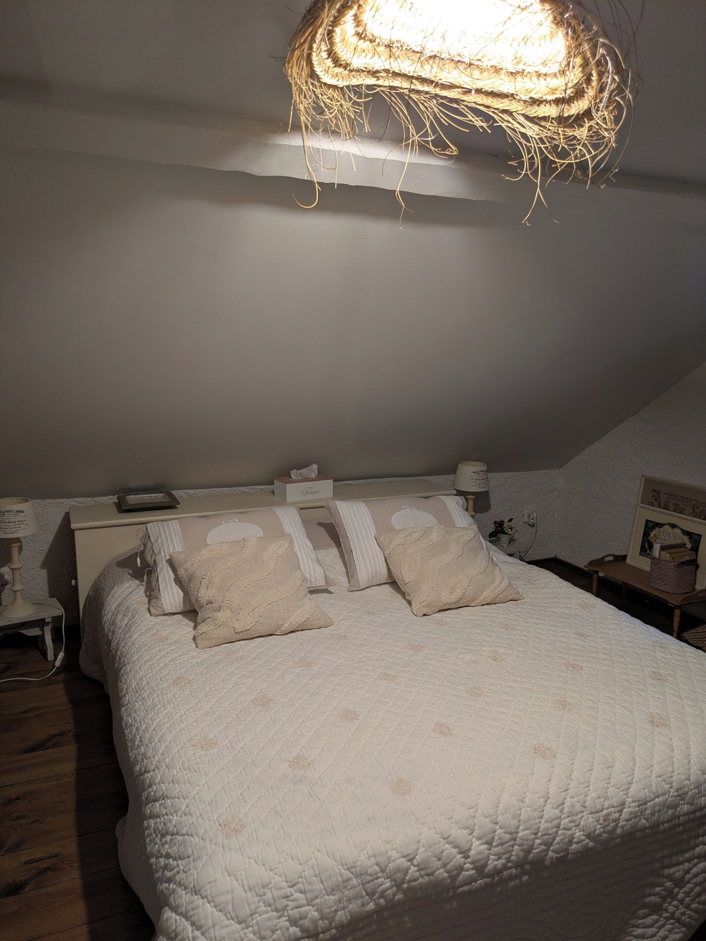 A bedroom with a bed, bedside tables, a lamp, and a wall-mounted light fixture.