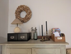 A desk with a lamp, a decorative wreath, a candle holder, and a box of books.