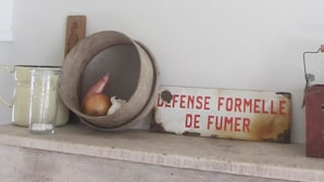 Un reloj rústico de pared con diseño antiguo, un balde de madera y un letrero con texto sobre una estantería.