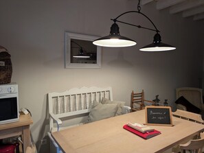 Une chambre avec une tête de lit blanche, une table en bois sur laquelle est posé un panneau, et deux lampes suspendues.