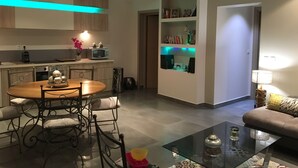 A modern kitchen with a dining area, a glass coffee table, and a sofa.