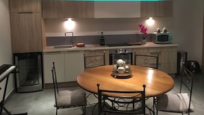 A modern kitchen with wooden cabinets, a central island with chairs, a microwave, and a kettle.