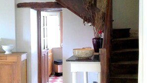 Un escalier en bois, avec un vase de fleurs séchées posé sur la plateforme.