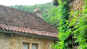 Un bâtiment en pierre avec un toit en tuiles, des fenêtres en arc de cercle et une petite entrée.
